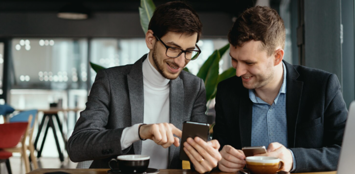 Dois homens usando smartphones em café moderno