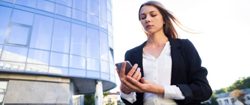 Mulher de negócios olhando para o celular em área urbana