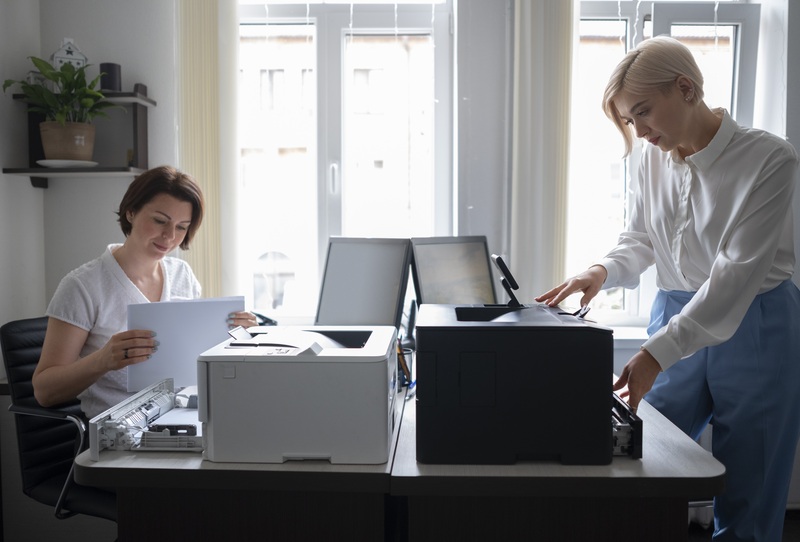 Duas mulheres trabalhando com impressoras em escritório moderno