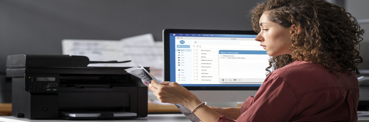 Mulher usando impressora enquanto trabalha em computador