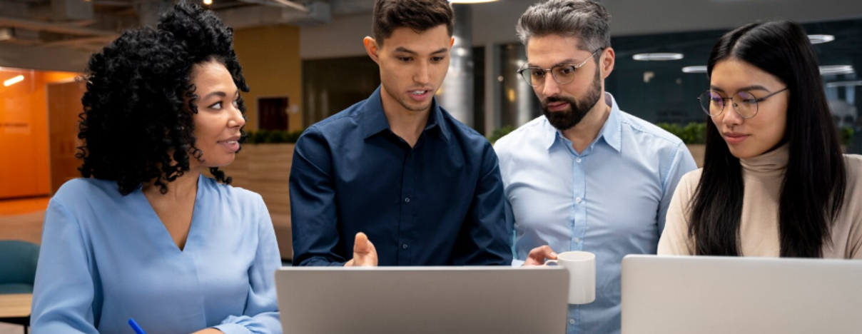 Quatro pessoas discutindo em frente a laptops