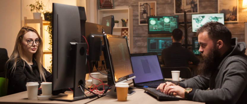 Duas pessoas trabalhando em computadores em escritório moderno